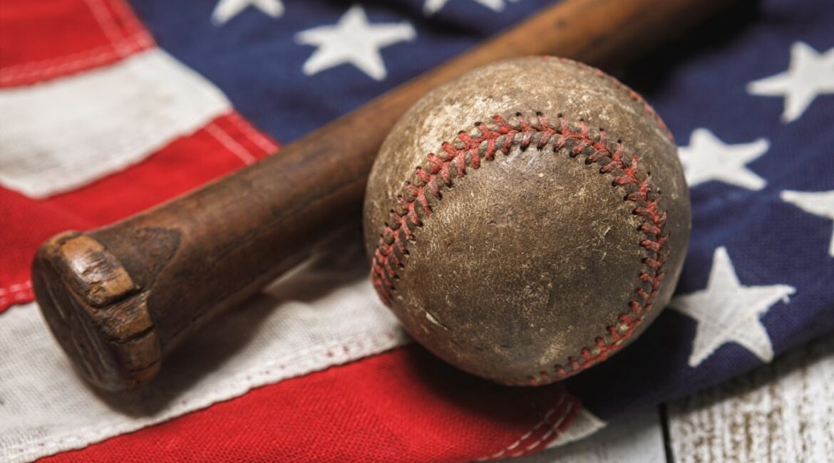 Image of an old baseball and wooden bat on an American flag