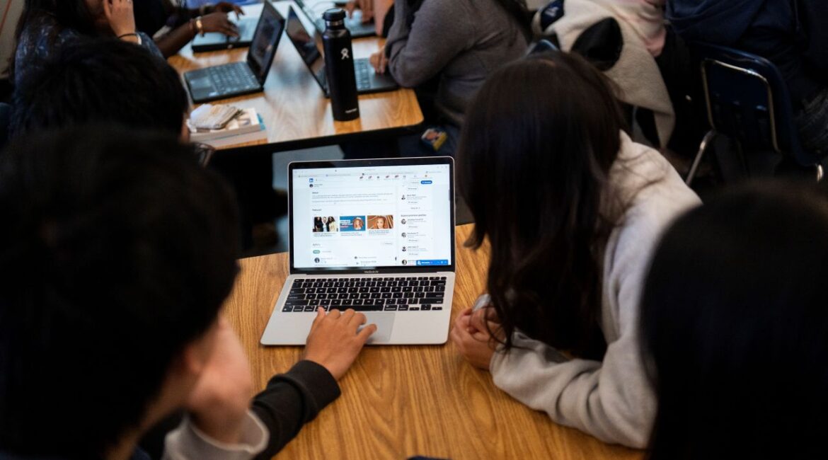 Image of students checking social media information on a laptop