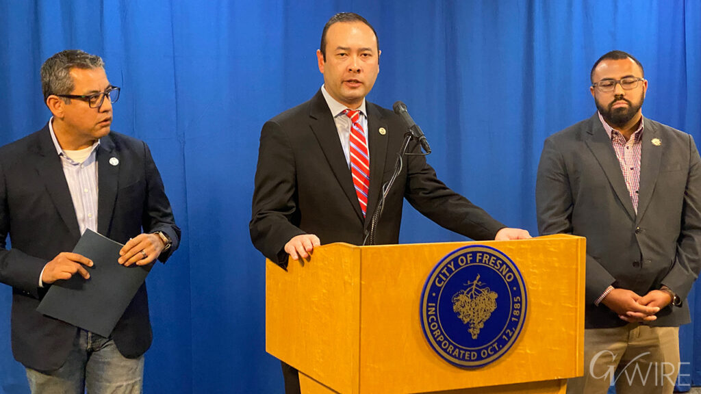Fresno City Attorney Andrew Janz stands at a podium and provides an update to a legal challenge to the city's tobacco shop regulations, along with city councilmembers Miguel Arias and Nelson Esparza
