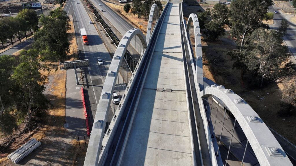 Aerial view of a concrete high-speed rail overpass over Highway 99 in Fresno. Cars pass under the uncompleted structure on the freeway below
