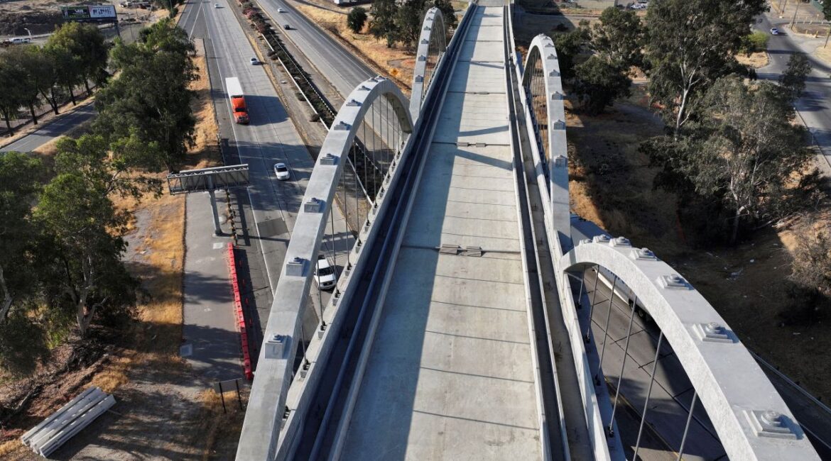 Aerial view of a concrete high-speed rail overpass over Highway 99 in Fresno. Cars pass under the uncompleted structure on the freeway below