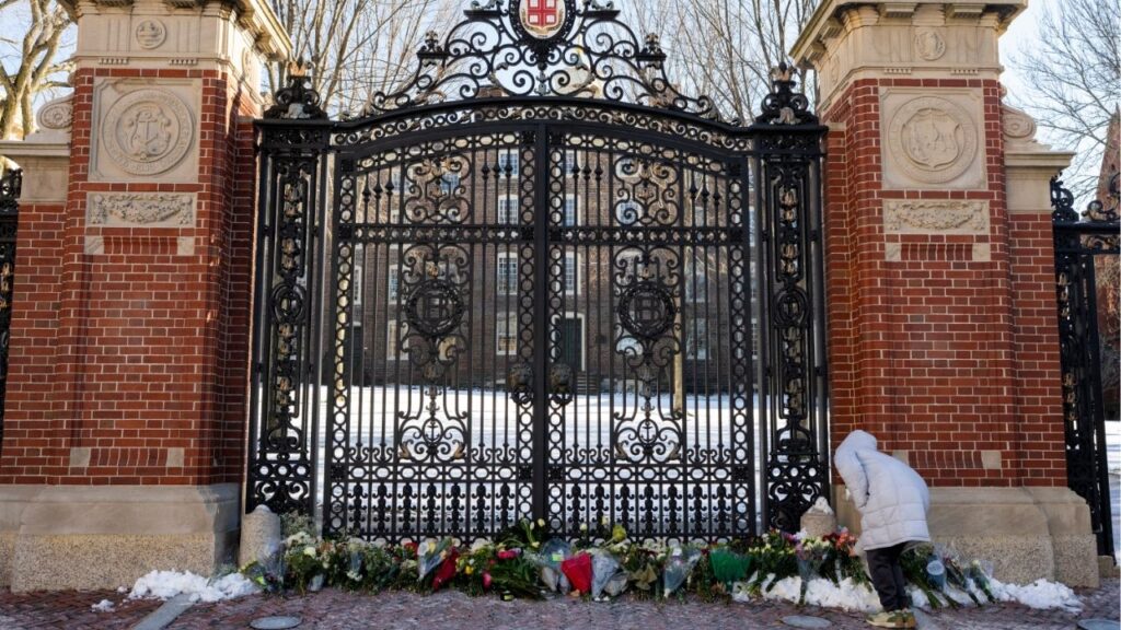 Hannah Chen, a junior at Brown University, leaves flowers at the Van Wickle Gates at the Brown University campus in Providence, R.I., on Monday, Dec. 15, 2025. The authorities on Thursday identified a person of interest in the shooting at Brown University and are investigating whether there is a possible connection to the killing of a Massachusetts Institute of Technology professor, according to a law enforcement official who was briefed on the matter but was not authorized to speak about the investigation. (Christopher Capozziello/The New York Times)