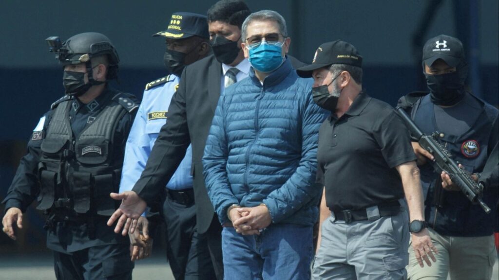 Honduras former President Juan Orlando Hernandez is escorted by authorities as he walks towards a plane of the U.S. Drug Enforcement Administration (DEA) for his extradition to the United States, to face a trial on drug trafficking and arms possession charges, at the Hernan Acosta Mejia Air Force base in Tegucigalpa, Honduras April 21, 2022. (Reuters File)