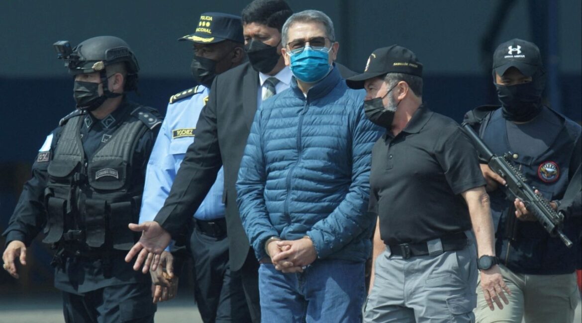 Honduras former President Juan Orlando Hernandez is escorted by authorities as he walks towards a plane of the U.S. Drug Enforcement Administration (DEA) for his extradition to the United States, to face a trial on drug trafficking and arms possession charges, at the Hernan Acosta Mejia Air Force base in Tegucigalpa, Honduras April 21, 2022. (Reuters File)