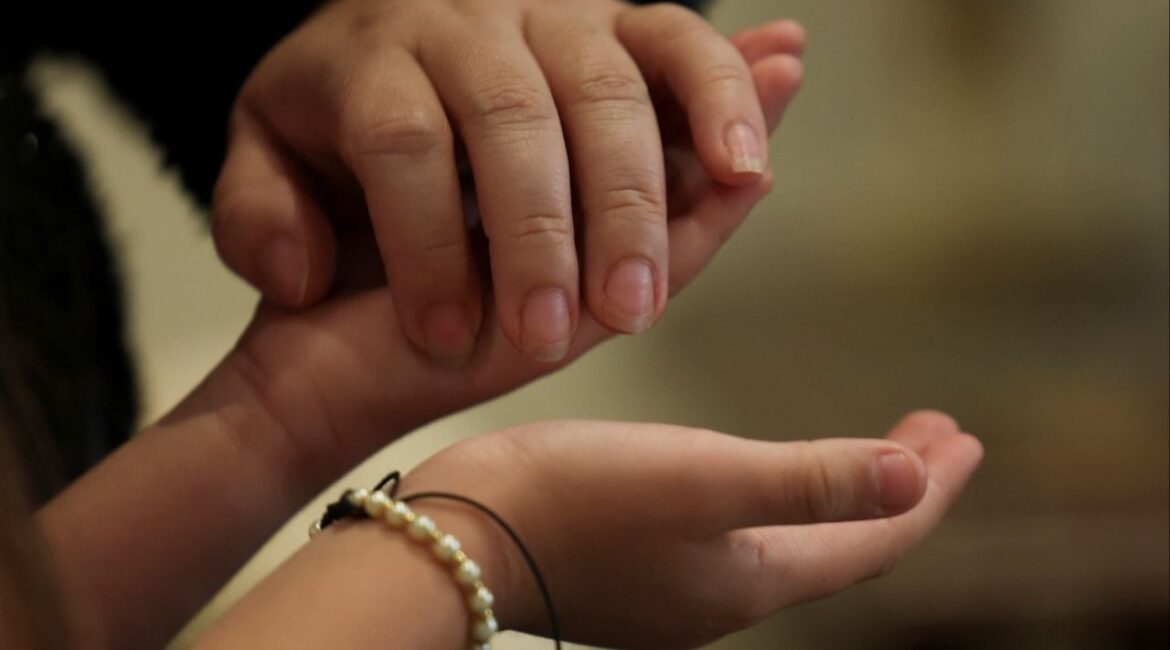 Kelly Johana Vargas Lozano, 30, holds the hands of her daughter Maria Paula Herrera Vargas, 6, at the place where they are staying after being deported from the United States, amid the immigration crackdown by the U.S. government, in Bogota, Colombia, November 19, 2025. (Reuters/Luisa Gonzalez)