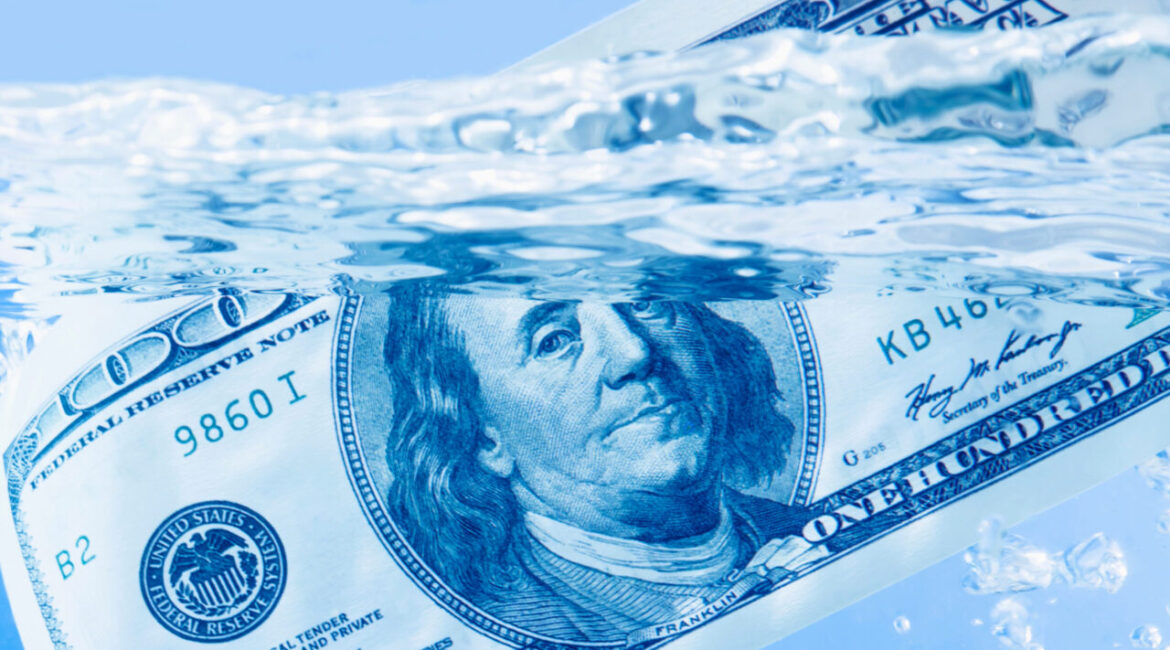Image of a $100 bill floating in water with a sparkling blue hue