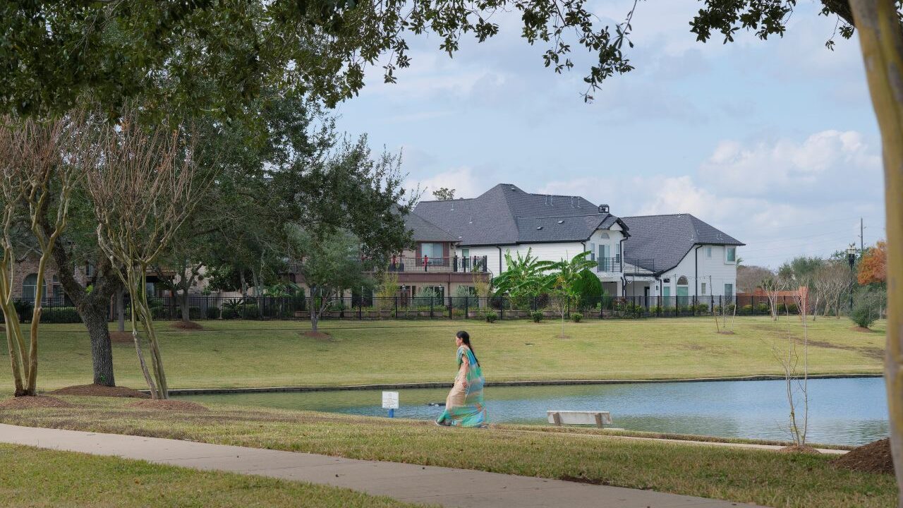 An Indian American woman walks near at lake in a beautiful neighborhood in Sugar Land, Texas