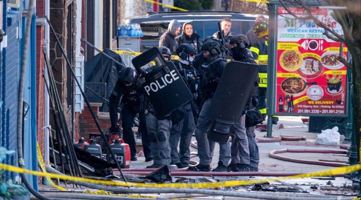 Police officers and a SWAT team at the scene where the suspect in a bow-and-arrow killing was hiding in Kearny, N.J., on Sunday, Dec. 21, 2025. A man was arrested on Sunday after a bizarre killing with a bow and arrow, an hours long standoff and an early-morning fire that shut down a street in a New Jersey suburb. (Dakota Santiago/The New York Times)