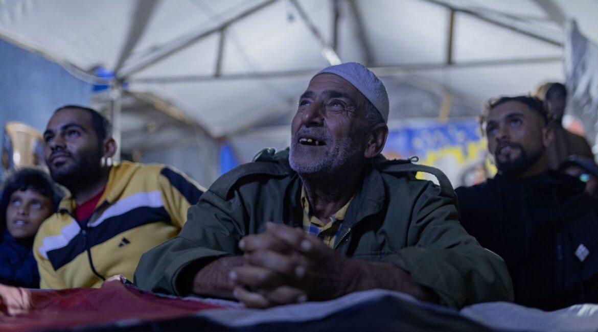 Image of four Palestinian men in a cafe watching their national soccer team play Saudi Arabia on a screen that is out of view.
