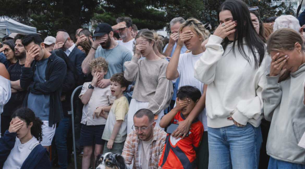 Image of mourners covering their eyes while praying for those killed in a mass shooting in Australia