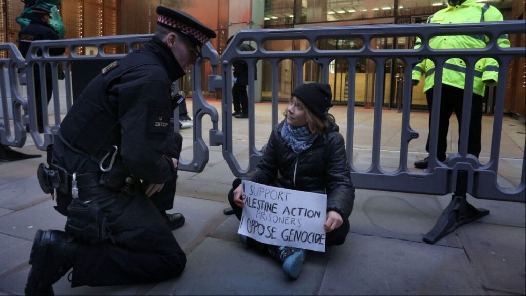 Swedish activist Greta Thunberg speaks to a police officer during a pro-Palestinian protest as she holds a sign that says she supports prisoners linked to Palestine Action, an organisation which the British government has proscribed as a terrorist group, in London, Britain, December 23, 2025. Prisoners for Palestine/Handout via REUTERS