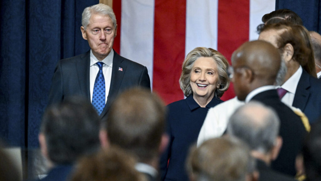 Image of Bill Clinton and Hilllary Clinton, both dressed in dark formal attire inside the Capitol Rotunda on the morning of Donald Trump's second inauguration.