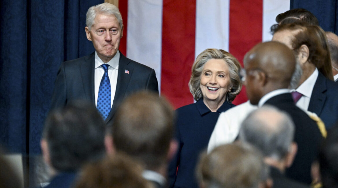 Image of Bill Clinton and Hilllary Clinton, both dressed in dark formal attire inside the Capitol Rotunda on the morning of Donald Trump's second inauguration.