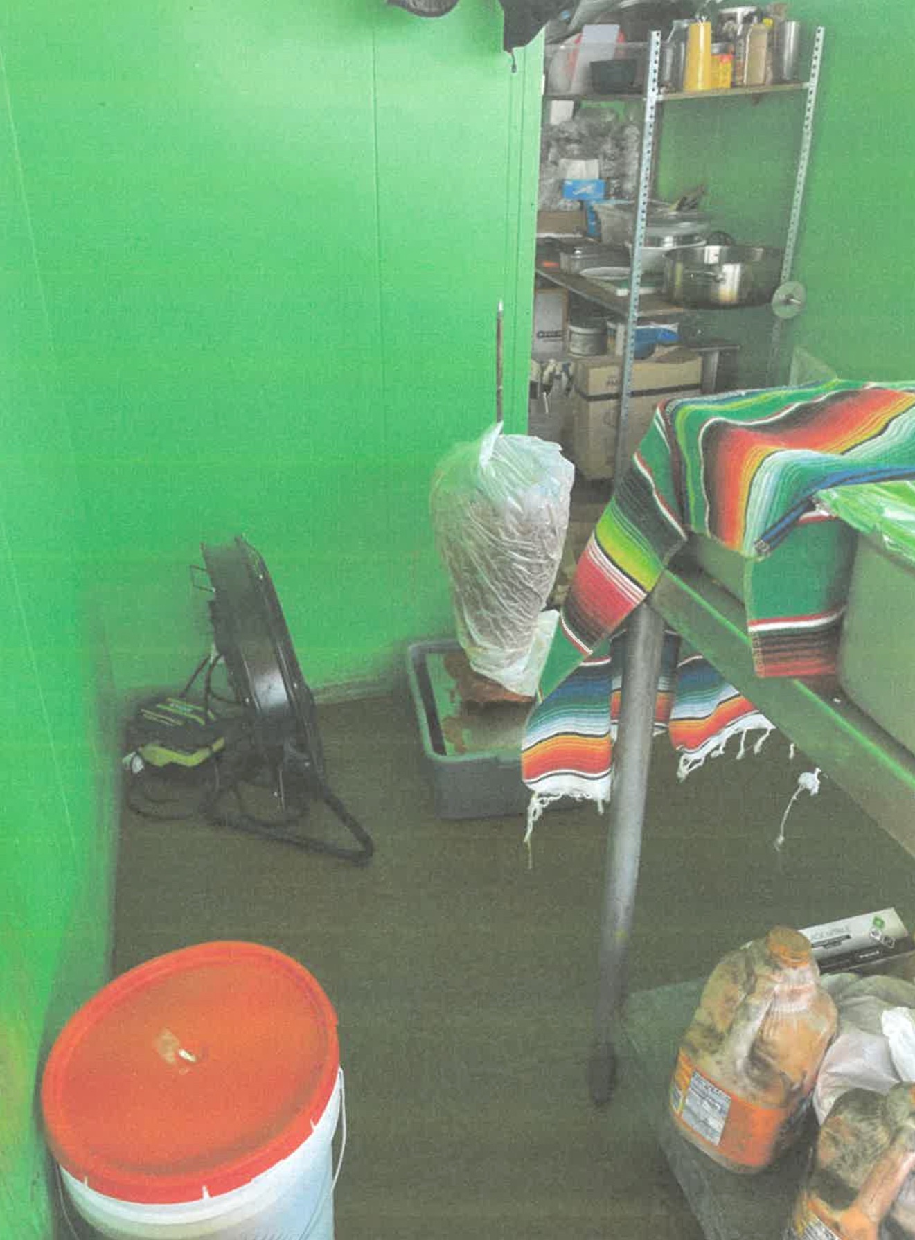 Vertical broiler with meat from the night before on the floor at room temperature being cooled by a fan.