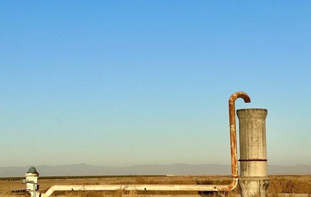 Image of a blue sky and a groundwater well in a farm field in the San Joaquin Valley