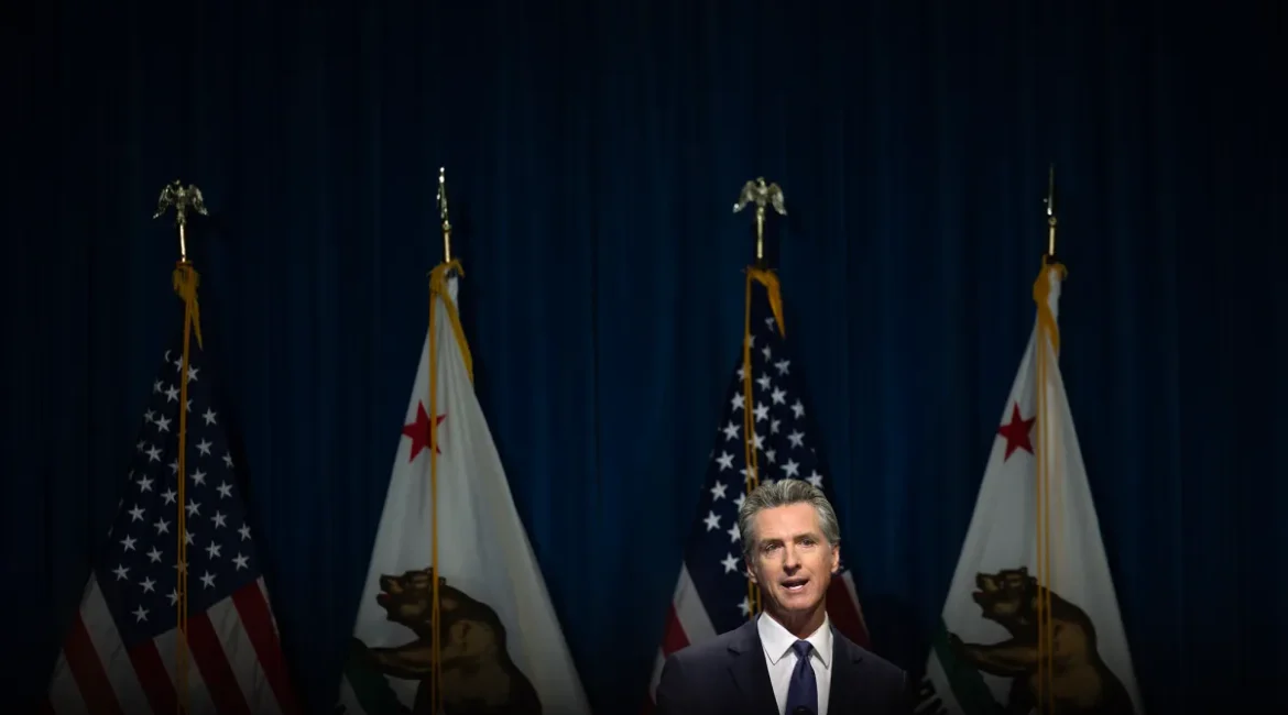 Image of California Gov. Gavin Newsom speaking at the state Capitol. Behind him are US and California flags