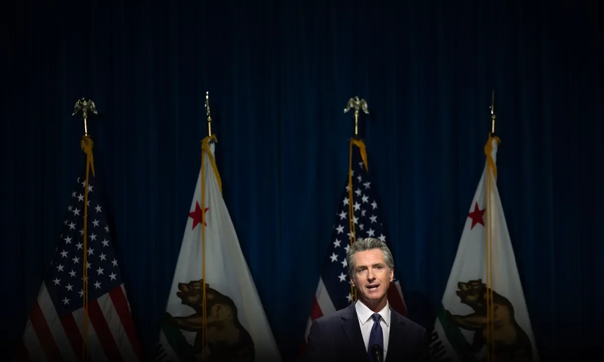 Image of California Gov. Gavin Newsom speaking at the state Capitol. Behind him are US and California flags