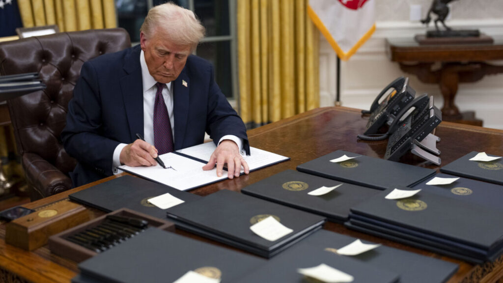 Image of President Trump at his Oval Office desk signing presidential pardons on the first day of his second term