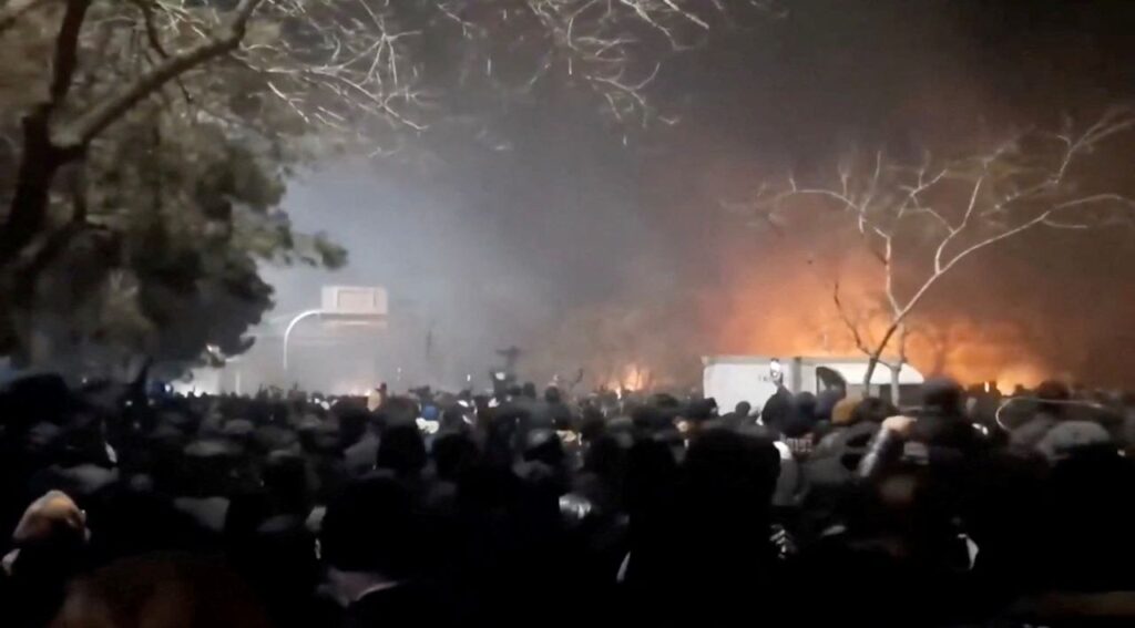 Image of flames and smoke rising above protesters in Iran