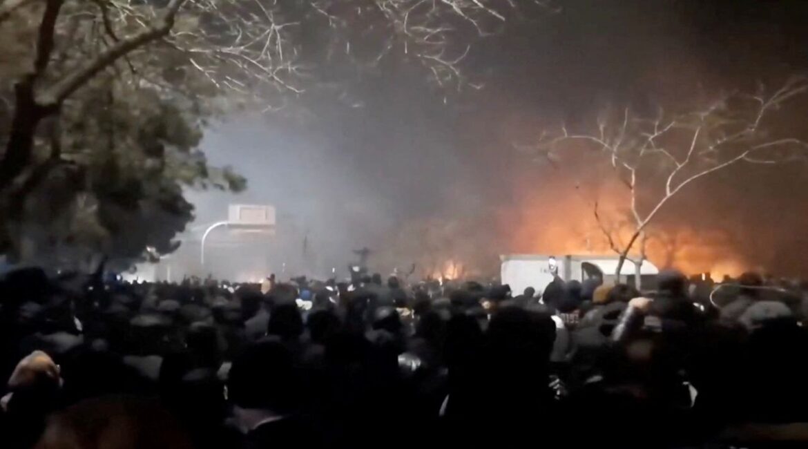 Image of flames and smoke rising above protesters in Iran