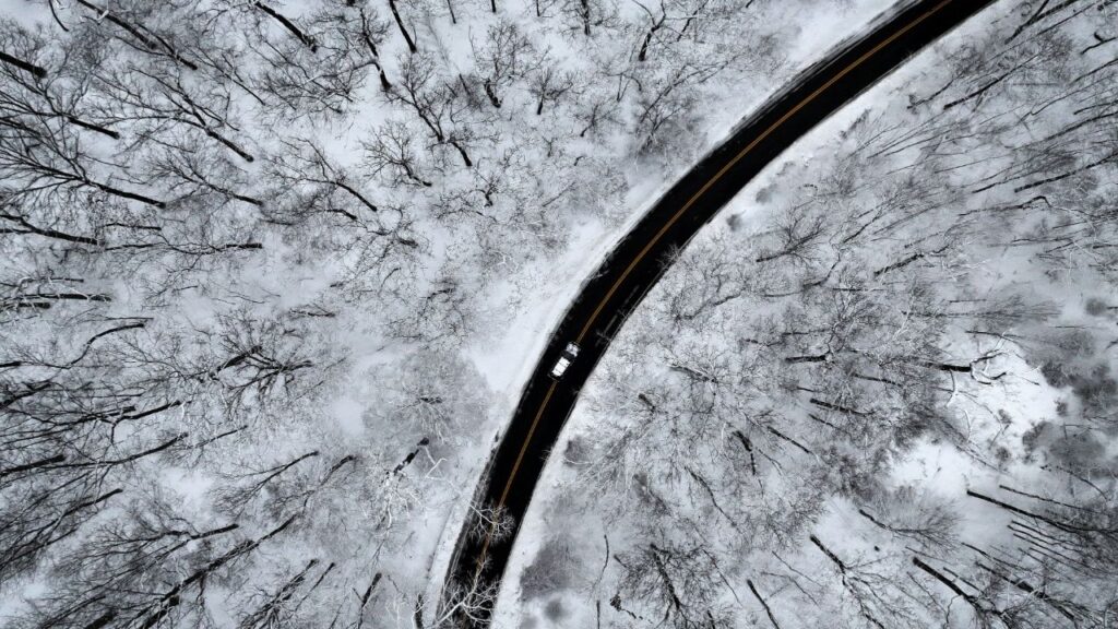 A drone view of a car driving through the snow covered woods of Blauvelt State Park in Orangetown, New York, U.S., December 27, 2025. (Reuters/Mike Segar)