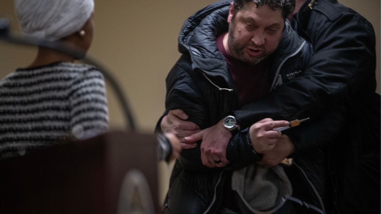 A man is held back after attacking Rep. Ilhan Omar (D-Minn.) during a town hall in Minneapolis, on Tuesday, Jan. 27, 2026. The man rushed the lectern and appeared to spray Omar with a strong-smelling liquid before he was tackled by security. Omar, visibly shaken after the assault, insisted to her staff and security that she would continue. (Victor J. Blue/The New York Times)