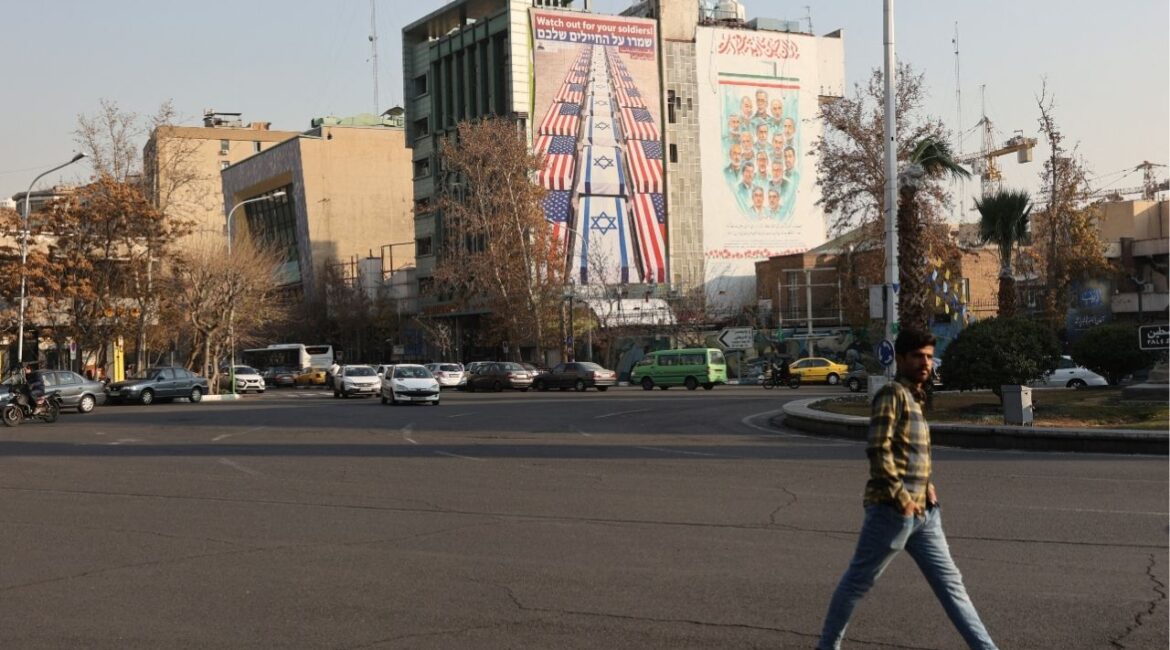 A man walks near an anti-U.S. and anti-Israeli billboard displayed on a building in Tehran, Iran, January 4, 2026. (Majid Asgaripour/WANA (West Asia News Agency) via Reuters)