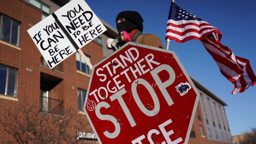 A person holds a stop sign, a placard and a U.S. flag as community members protest after federal agents fatally shot a man while trying to detain him, in Minneapolis, Minnesota, U.S., January 24, 2026. (Reuters/Seth Herald)