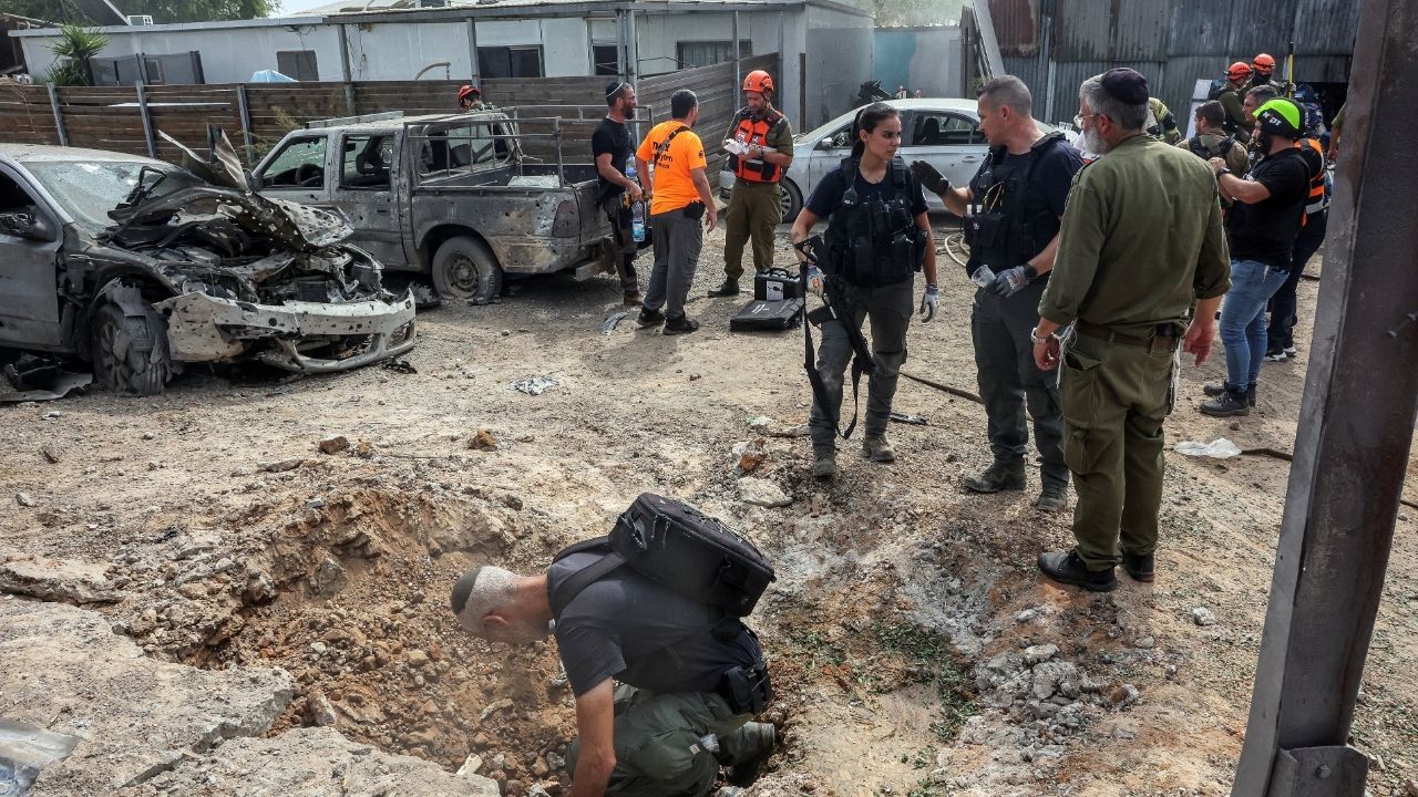 A security official investigates the crater formed when a projectile landed, after Hamas' armed wing said it attacked Tel Aviv with a missile salvo, amid the ongoing Israel-Hamas conflict, in Kfar Chabad, Israel, October 7, 2024. (Reuters File)