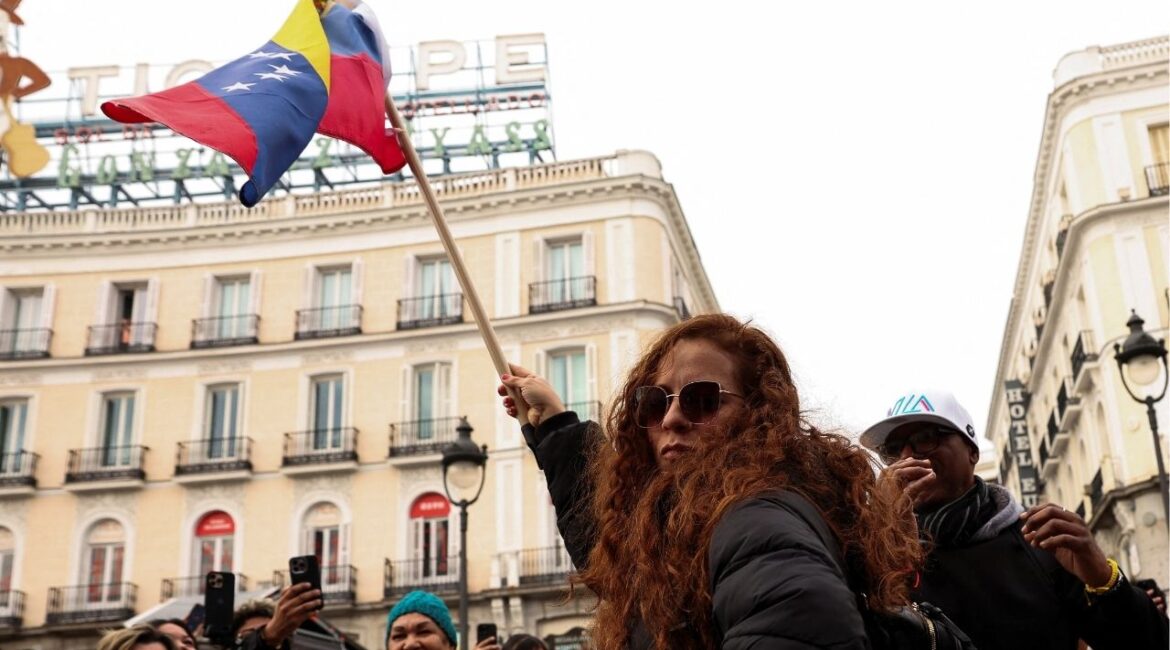 A woman waves a Venezuelan flag, as people react to the news after U.S. President Donald Trump said the U.S. has struck Venezuela and captured its President Nicolas Maduro, in Madrid, Spain, January 3, 2026. REUTERS/Violeta Santos Moura