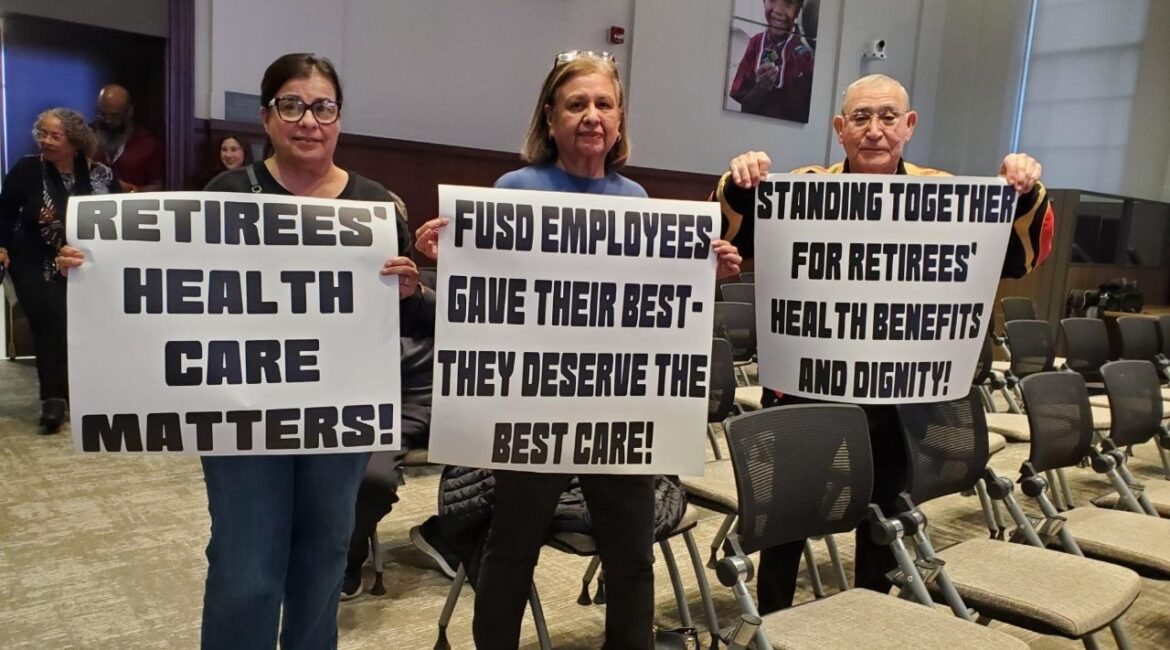Attendees at Wednesday, Jan. 14, 2026, night’s Fresno Unified board meeting brought signs addressing concerns over retiree health insurance. (GV Wire/Jahziel Tello)