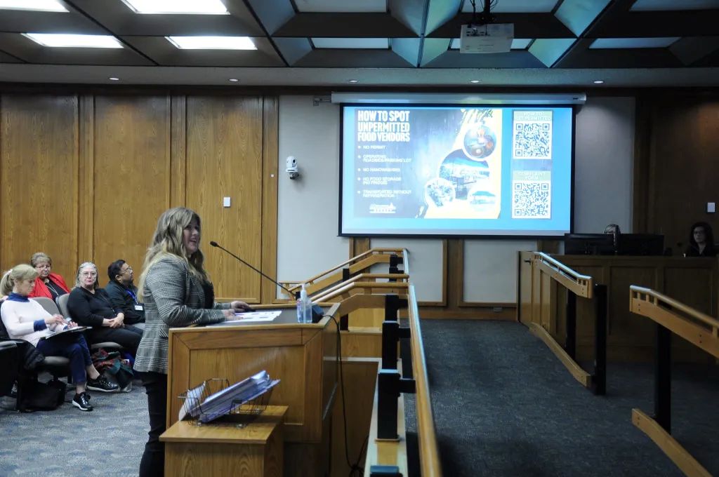 Image of Amanda Duran in a gray jacket and black pants speaking at a Merced County Supervisors meeting 