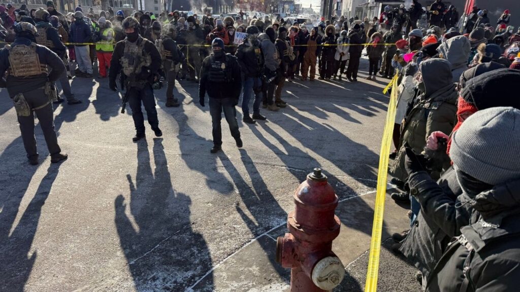 Demonstrators and civilians surround a perimeter held by federal agents near the intersection of 26th Street and Nicollet Avenue in Minneapolis, where federal law enforcement agents shot a person earlier on Saturday, Jan. 24, 2026. The scene was cordoned off with crime scene tape, as dozens of protesters, some wearing gas masks and goggles, blew whistles. ICE agents from Enforcement and Removal Operations were on site, as were several agents wearing U.S. Bureau of Prison Uniforms. (David Guttenfelder/The New York Times)