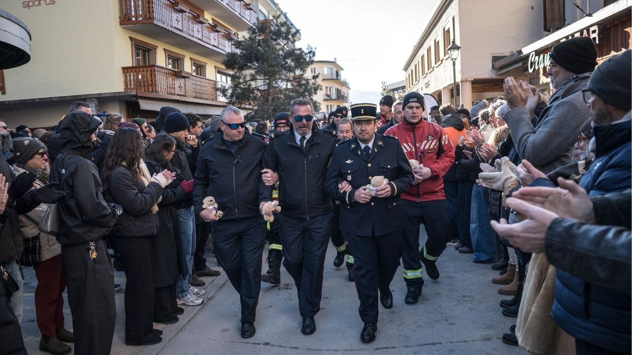 Firefighters who responded to a blaze at the Le Constellation bar are applauded by onlookers as they march to the site during a commemorative event in Crans-Montana, Switzerland, on Sunday, Jan. 4, 2026. In Crans-Montana, the ski resort where at least 40 people died in a New Year’s Day blaze, residents were struggling to come to terms with one of the worst such disasters in Switzerland’s history. (Sergey Ponomarev/The New York Times)