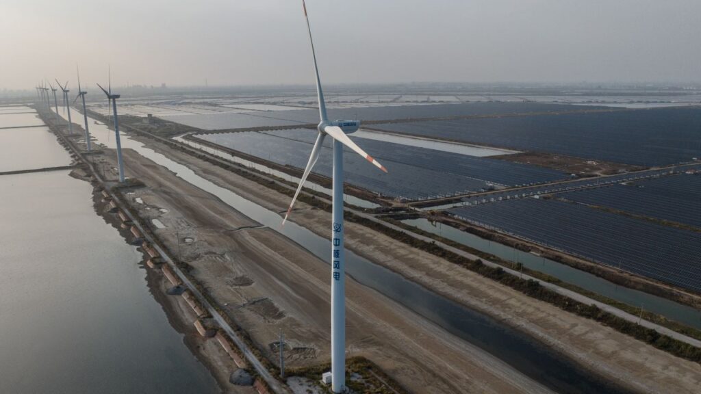Image of a wind turbine and coal-powered plant in Weifang, China on a hazy day in 2023