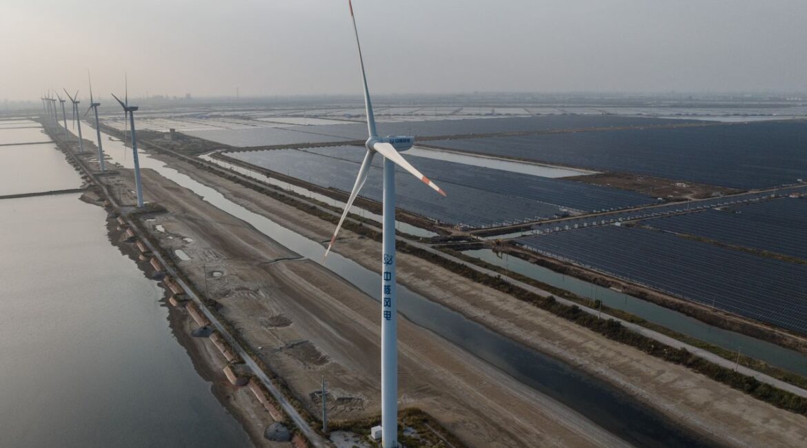 Image of a wind turbine and coal-powered plant in Weifang, China on a hazy day in 2023
