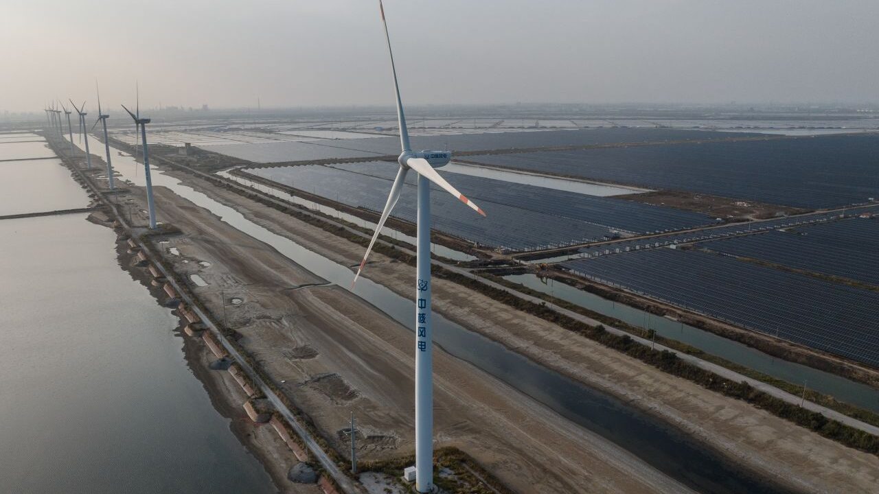 Image of a wind turbine and coal-powered plant in Weifang, China on a hazy day in 2023