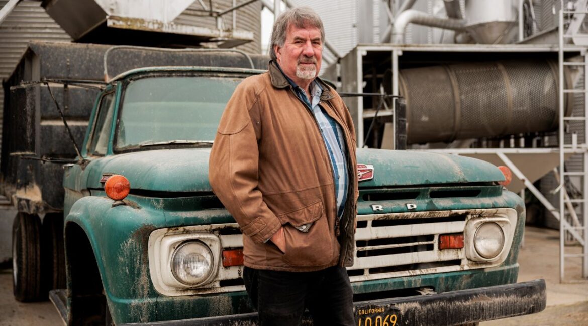 Image of the late Rep. Doug LaMalfa, a Republican, at his rice farm in Richvale. He's wearing a barn jacket and standing in front of a green Ford flatbed truck.