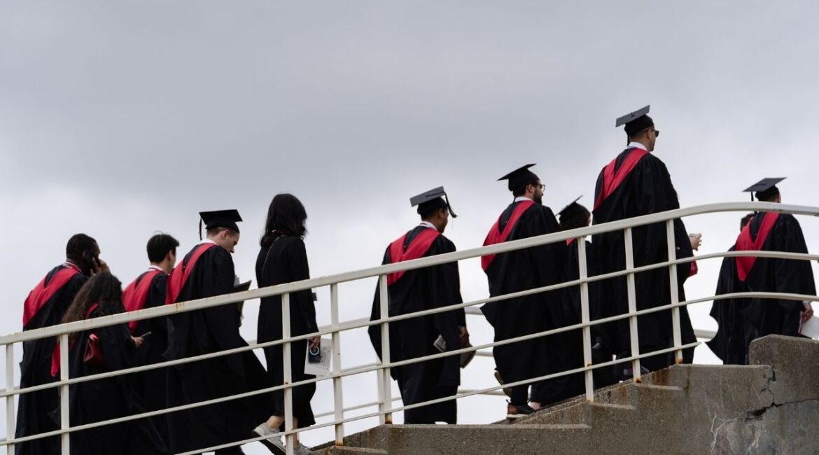 Harvard University students cross a footbridge after Harvard University’s 374th Commencement in Cambridge, Mass. May 29, 2025. The Education Department has temporarily paused a plan to seize tax refunds and begin garnishing the wages of borrowers who have defaulted on their student loans. (Sophie Park/The New York Times)