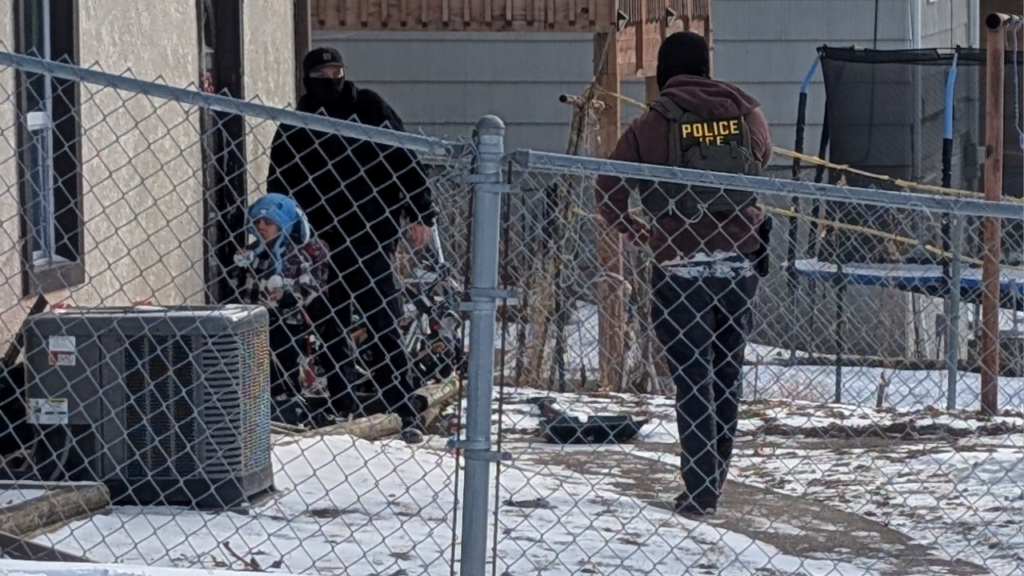ICE agents stand next to a boy, who a witness identified as Liam Conejo Ramos, a five-year-old that school officials said was detained in Minneapolis, Minnesota, U.S., January 20, 2026. Rachel James/via REUTERS