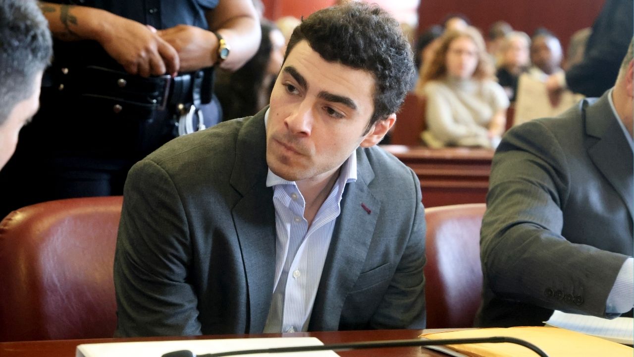 Luigi Mangione, charged in the murder of UnitedHealthcare chief executive Brian Thompson, confers with one of his attorneys as he awaits the start of a pretrial hearing in State Supreme Court in Manhattan, Dec. 11, 2025. State prosecutors in New York asked a judge on Wednesday to set a July trial date for the murder case against Luigi Mangione, months ahead of a parallel federal trial in which he is charged with killing a health care executive in Midtown. (Jefferson Siegel/The New York Times)