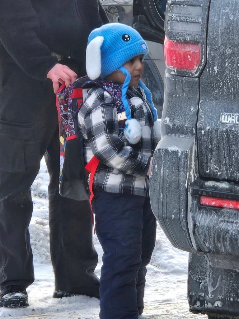 Image of a 5-year-old boy bundled in winter gear being detained outside by ICE agents