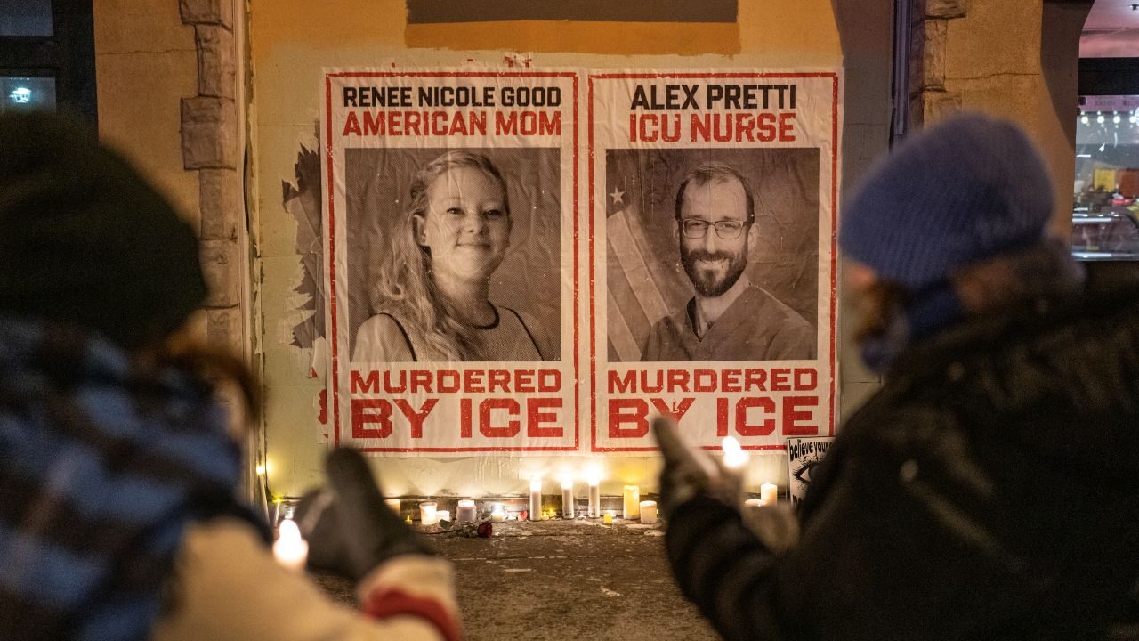 Image of mourners placing candles under posters of Renee Good and Alex Pretti on a cold night in Minneapolis.