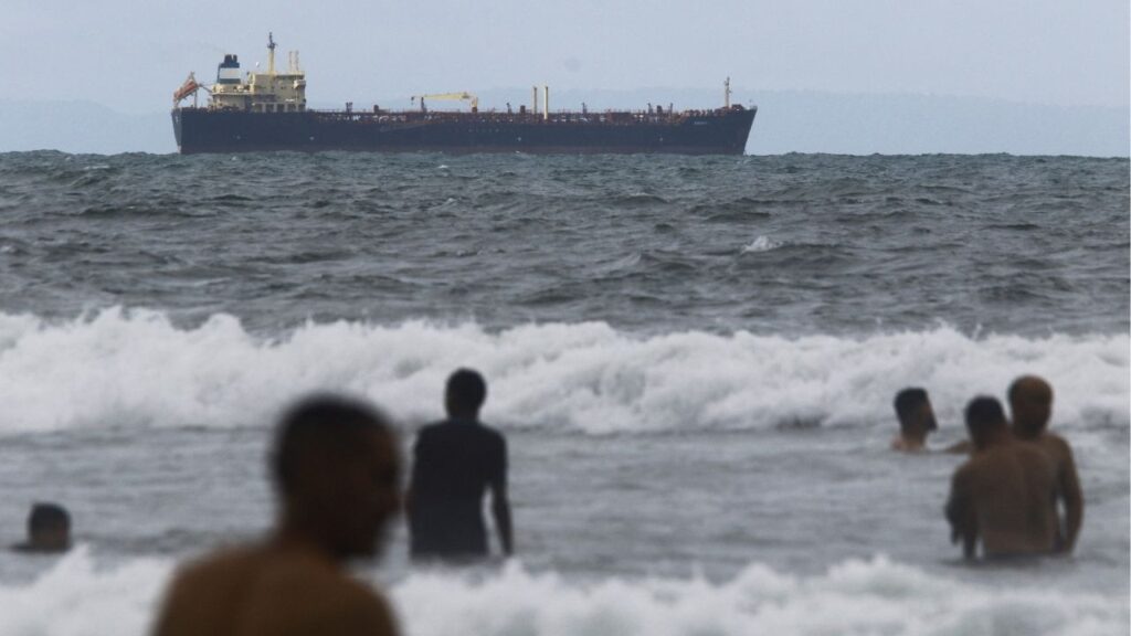 People enjoy the ocean near the Comoros-flagged oil tanker Evana, used to move oil between domestic ports in Venezuela, near El Palito terminal, in Puerto Cabello, Venezuela December 29, 2025. REUTERS/Juan Carlos Hernandez