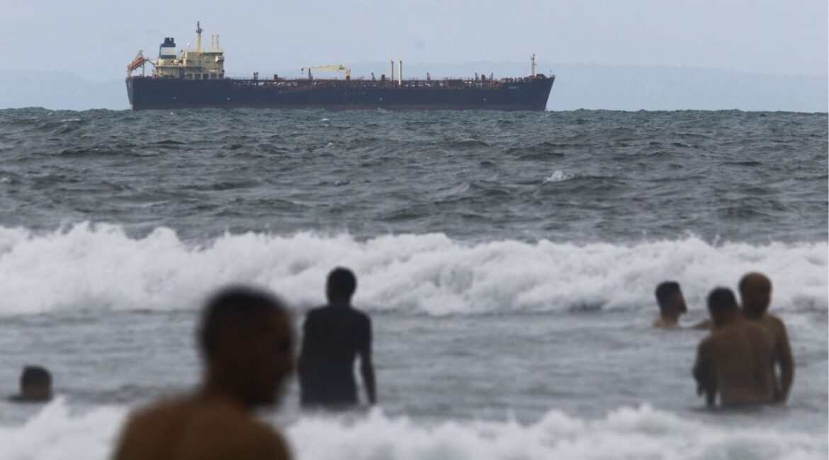 People enjoy the ocean near the Comoros-flagged oil tanker Evana, used to move oil between domestic ports in Venezuela, near El Palito terminal, in Puerto Cabello, Venezuela December 29, 2025. REUTERS/Juan Carlos Hernandez