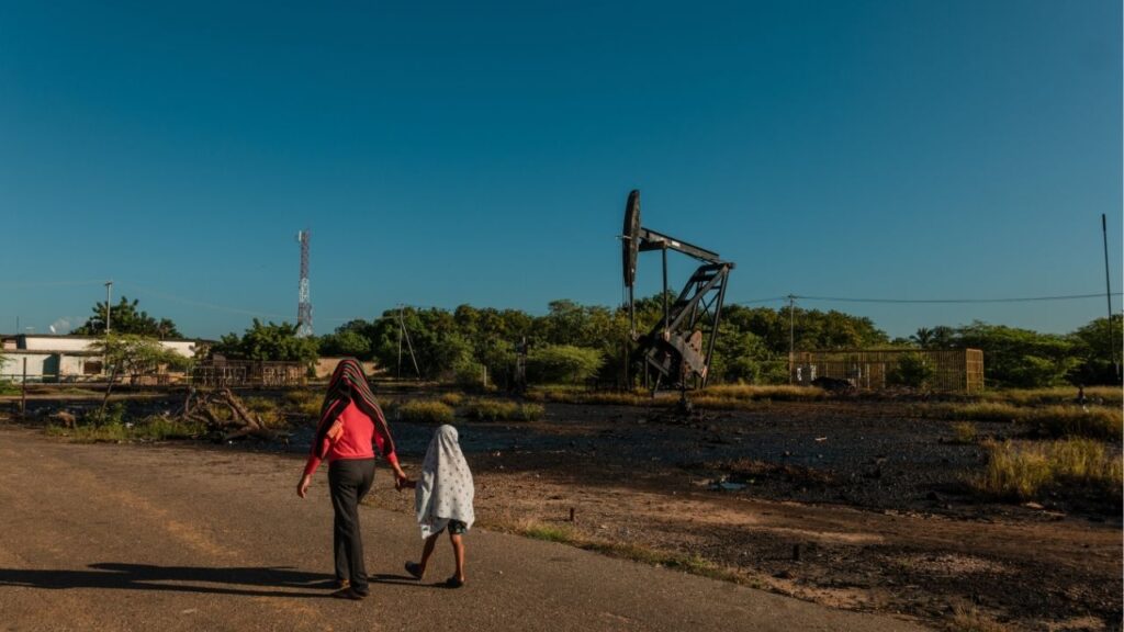 People walk by an overflowed oil rig in Cabimas, Venezuela, along the shoreline of Lake Maracaibo on Nov. 23, 2022. “We’re going to be using oil, and we’re going to be taking oil,” said President Trump about Venezuela in an interview with the New York Times. (The New York Times)