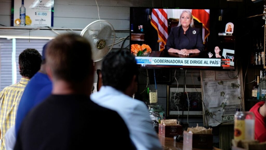 People watch television at a bar as Puerto Rico's Governor Wanda Vazquez Garced makes an address regarding the debt restructuring proposal filed in court by an oversight board, in San Juan, Puerto Rico, September 27, 2019. (Reuters/Ricardo Arduengo)