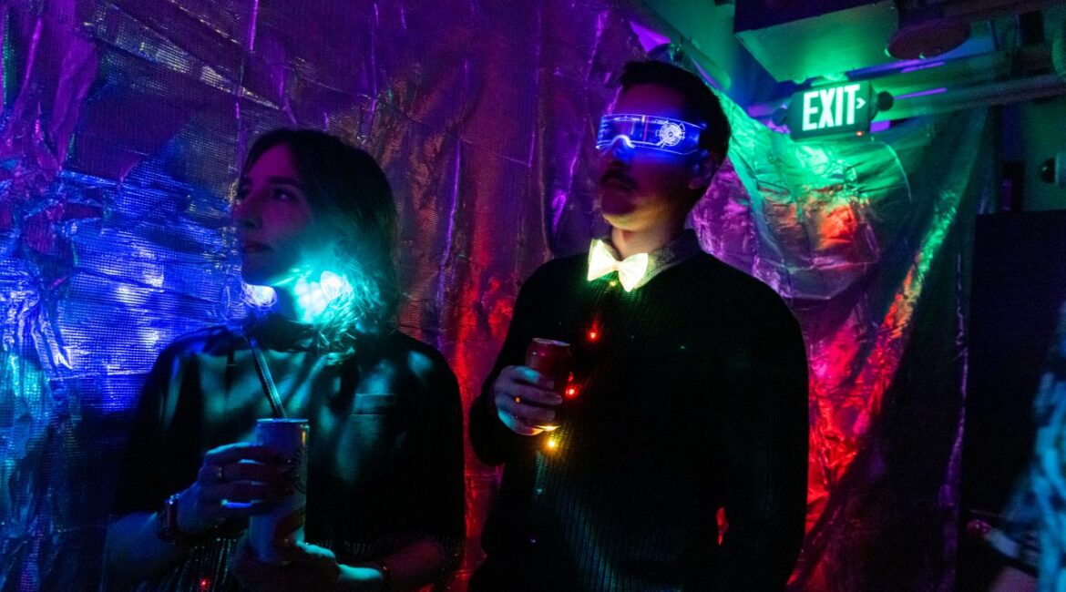 Image of a dark room cast in purple and red hues where people are attending a peptide rave