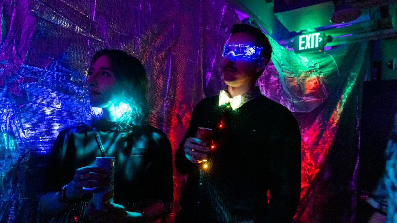 Image of a dark room cast in purple and red hues where people are attending a peptide rave