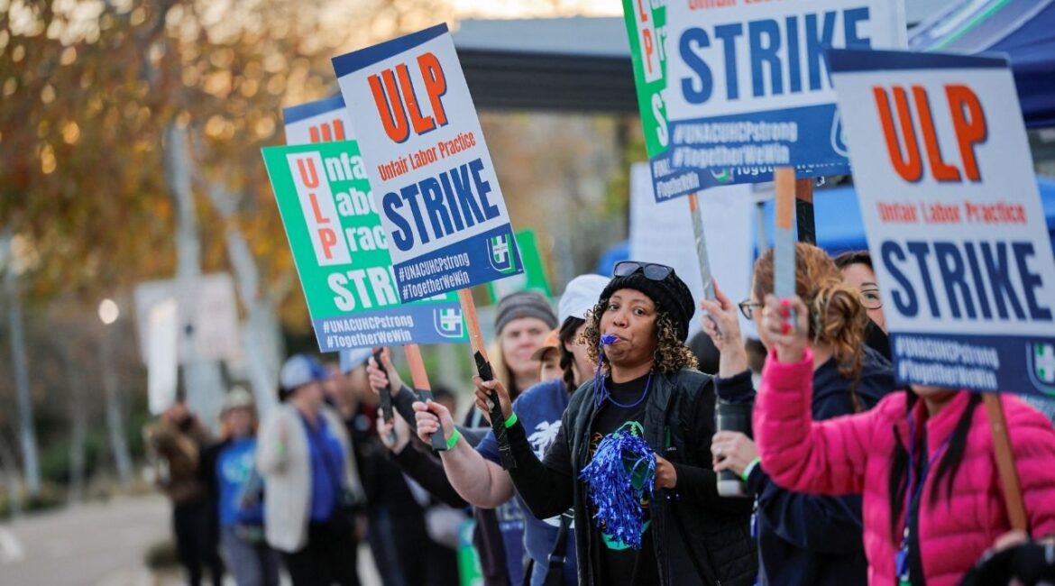 Striking members of the United Nurses Associations of California and Union of Health Care Professionals hold signs along the picket line outside a Kaiser Permanente hospital in San Diego, California, U.S., January 26, 2026. (Reuters/Mike Blake)